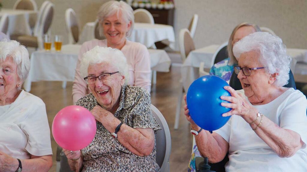 Older adult and family member sorting labeled boxes beside a compact assisted living apartment.